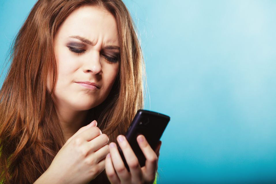 angry woman reading text on mobile phone