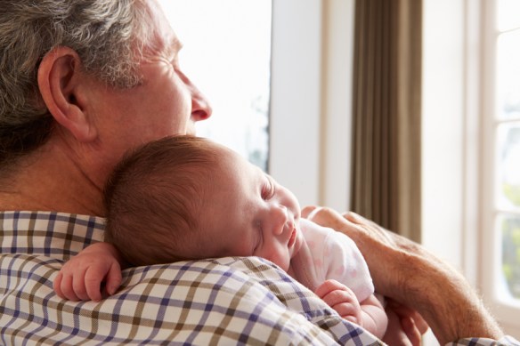 photo of man holding sleeping baby